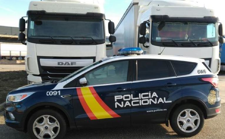 Un coche de la policía nacional junto a dos camiones
