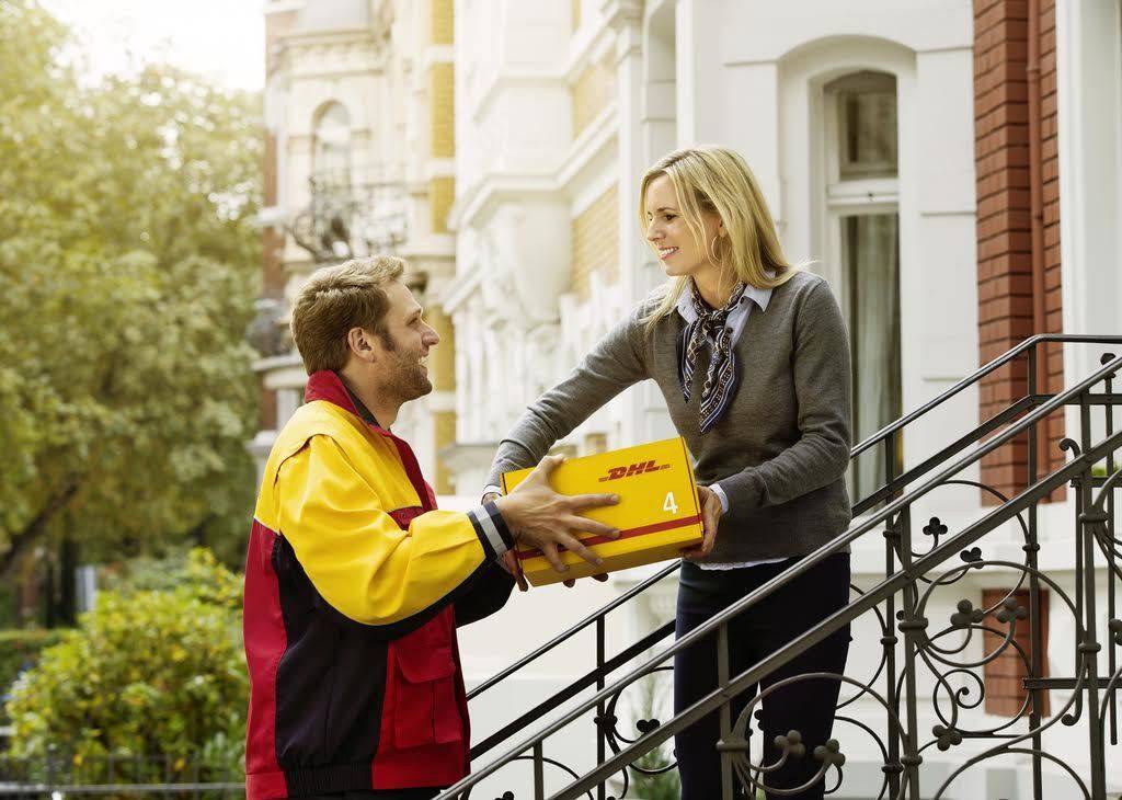 Trabajadora de DHL entregando un paquete a domicilio