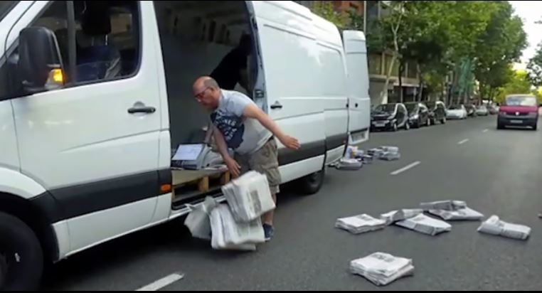 Un transportista tira en mitad de la calle ejemplares de periódicos