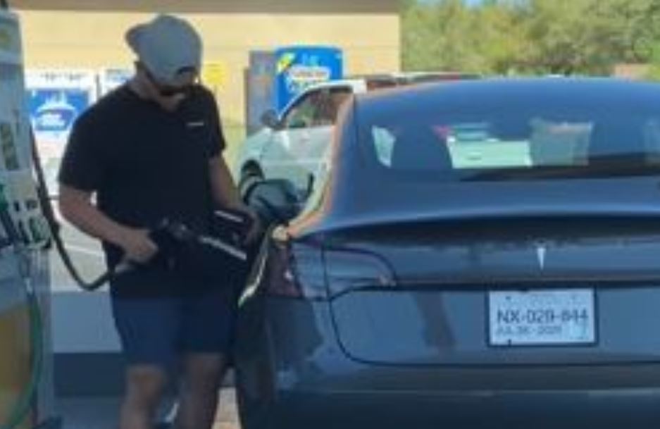 Imagen del hombre intentando echar gasolina en el depósito de un Tesla