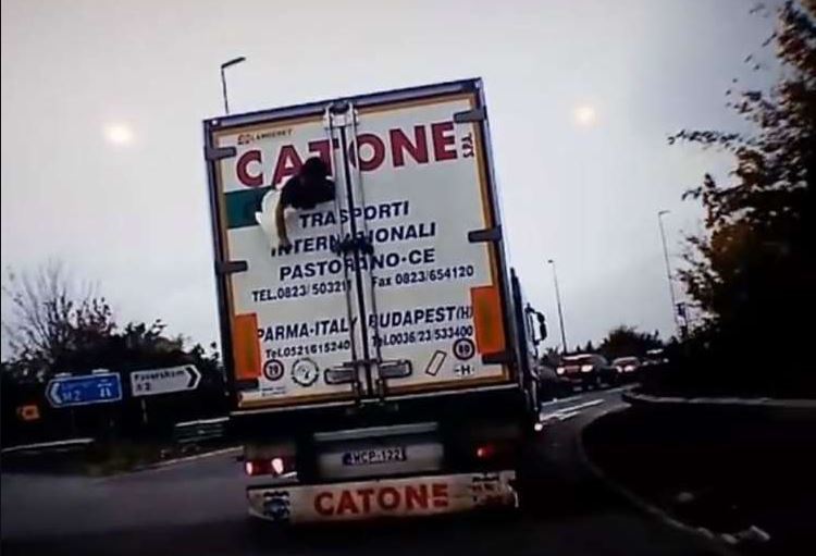 Imagen de un inmigrante intentando salir de un camión