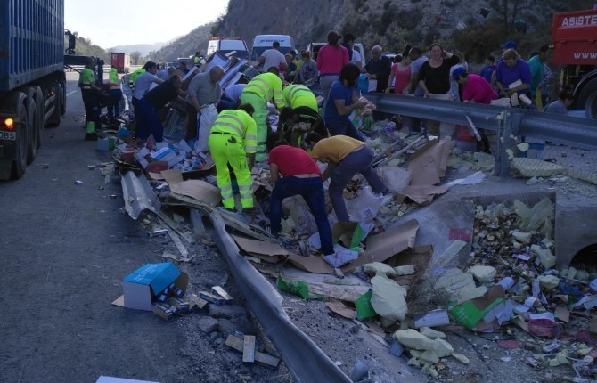 ACCIDENTE. Numerosas personas se afanan por recoger las latas de conservas que quedaron esparcidas por la cuneta de la Autovía A-44.