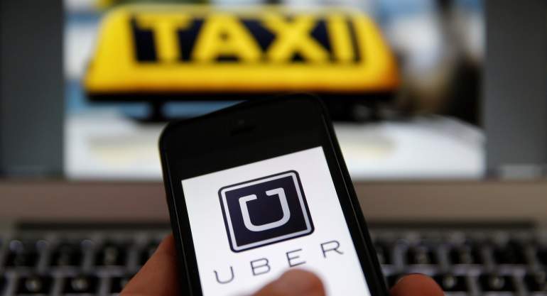 Imagen de un taxi y aplicación Uber