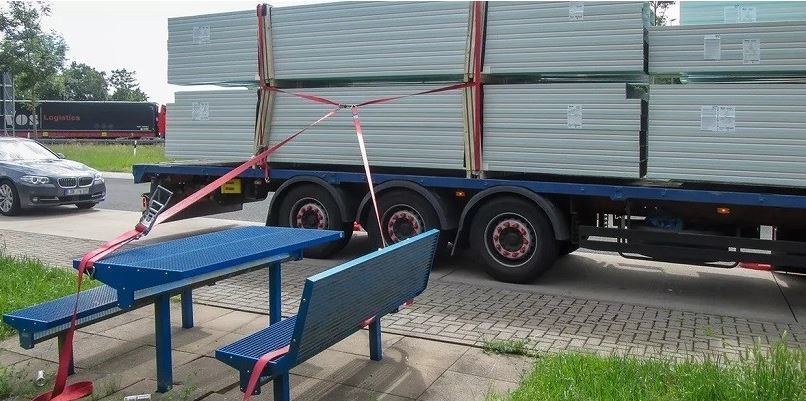 Imagen del camionero que usa mesa y sillas de un área de servicio para nivelar la carga