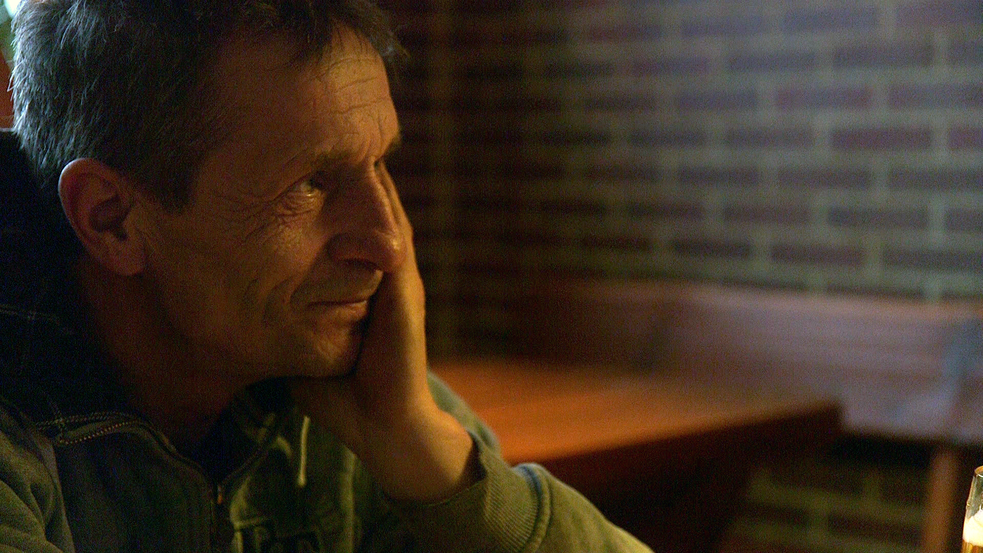 Un hombre se sienta con los partidarios de la mano para arriba en una mesa. © NDR