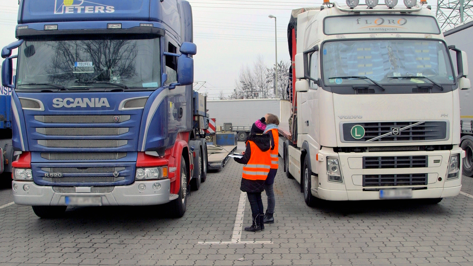 Dos personas en las chaquetas fluorescentes se interponen entre un camión. © NDR / 7 días 