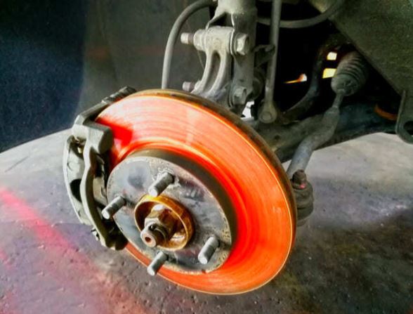 Disco de freno sobrecalentado al rojo vivo durante una frenada intensa.